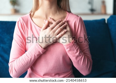 With all my heart. Cropped view of sincere and candid woman hold hand folded close to heart in peaceful sign. Close up of gesture expressing heartfelt thank for help and support