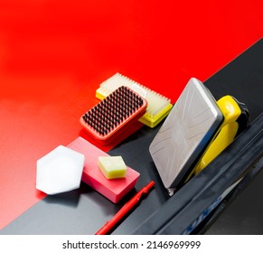 All the necessary tools for preparing skis and snowboards. Scraper, brush, grease, iron, sliding surface of a cross-country ski on a red and black background. Empty space for caption