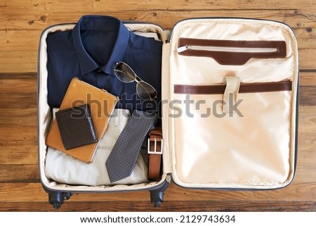 All packed and ready to go. High angle shot of a suitcase packed with various essentials for a traveling businessman.