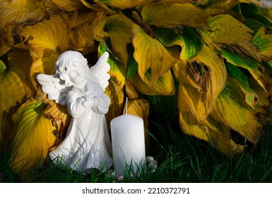 All Saints' Day. An Angel With A White Candle Against A Yellow Hosta.