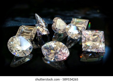 All shapes and cuts of diamonds, princess, cushion, heart, pear, marquise, radiant, Asscher, emerald and oval. Scattered diamonds laid out on black marble.