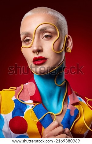 All I want to do is spread a little color. Studio shot of a stylish young woman posing against a red background.