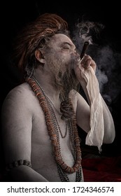 Allahabad, India- February 5 2019: Portrait of a Sadhu smoking at the Kumbh Mela festival , India. As in the Rastafarian religion, sadhus followers of Shiva often smoke marijuana.