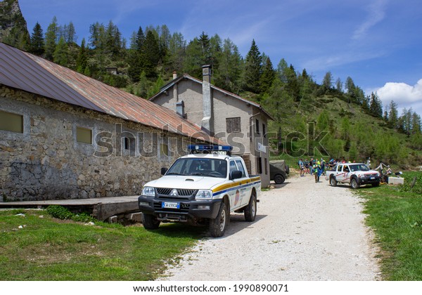 Alleghe, Italy - June 12, 2021: Civil\
protection machines and people near Malga Pioda (1816 m) under the\
Civetta Group,\
Dolomites.