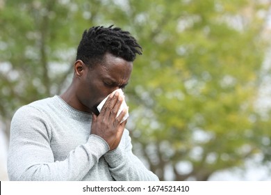 Allergic black man blowing on wipe in a park on spring season a sunny day