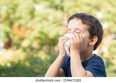 Allergic child sneezing covering nose with wipe in a park in spring or summer season - Powered by Shutterstock