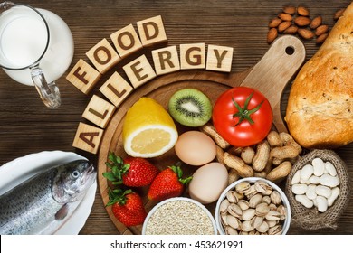 Allergy food concept. Allergy food as almonds, milk, pistachios, tomato, lemon, kiwi, trout, strawberry, bread, sesame seeds, eggs, peanuts and bean on wooden table