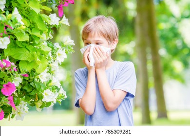 Allergy. Little boy is blowing his nose near blossoming flowers