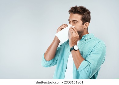 Allergy, sick and man blowing nose in tissue with flu, illness and virus on studio background. Health mockup, wellness and face of male person with handkerchief for hayfever sinus, cold and sneeze