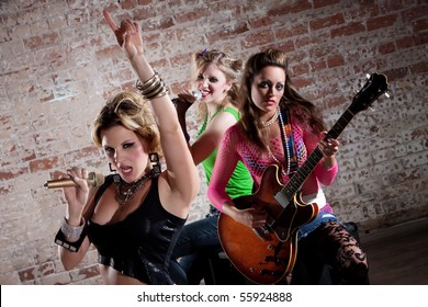 All-girl punk rock band performs in front of a brick background