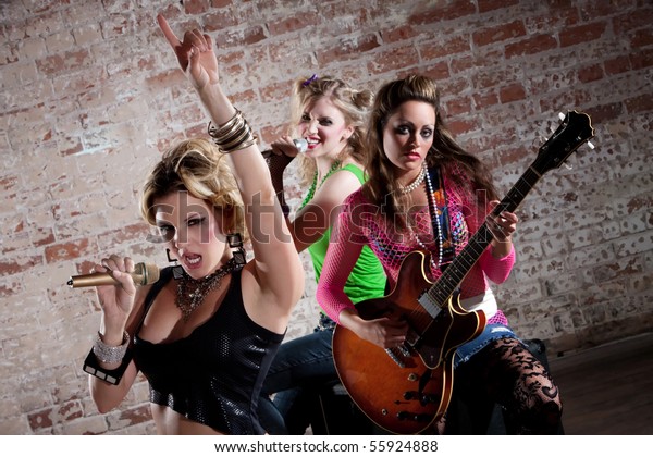 All-girl punk rock band performs in front of a\
brick background