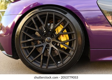 Alloy wheel with calipers and racing brakes of the sport car. Racing brake disc and low profile tyres. Race car test driving. Lower-profile tires of drag and drift cars. High-performance sports cars.