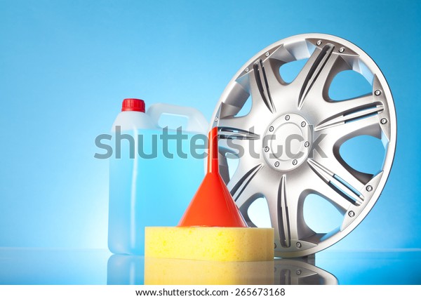 alloy wheel,funnel , a bottle of\
windshield washer fluid and sponge on blue\
background