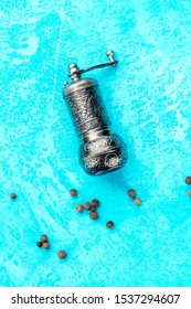 Allspice, Jamaica Pepper. Black Peppercorns With A Vintage Pepper Mill, Overhead Shot On A Turquoise Blue Background With Copyspace