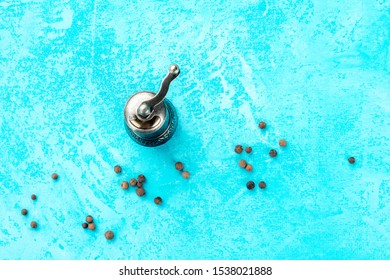 Allspice, Jamaica Pepper. Black Peppercorns With A Vintage Pepper Mill, Overhead Shot On A Blue Background With A Place For Text