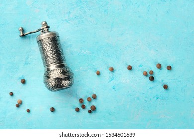 Allspice, Jamaican Pepper. Black Peppercorns With A Vintage Pepper Mill, Overhead Shot On A Blue Background With Copy Space. Culinary Flat Lay Design Template