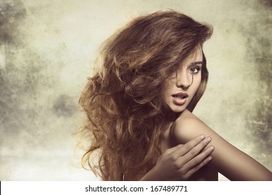 Alluring Young Girl Posing In Fashion Shoot With Naked Shoulder And Creative Bushy Hairdo 