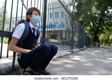 Almaty / Kazakhstan - 08.31.2020 : 
A Masked Middle School Student Sits Leaning Against The School Fence.