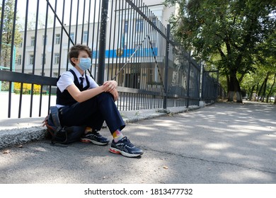 Almaty / Kazakhstan - 08.31.2020 : 
A Masked Middle School Student Sits Leaning Against The School Fence.