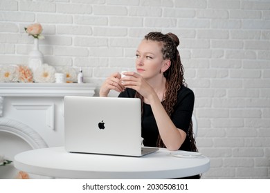 Almaty, Kazakhstan, July 12, 2021, A Female of European appearance poses at a table with an Apple laptop
