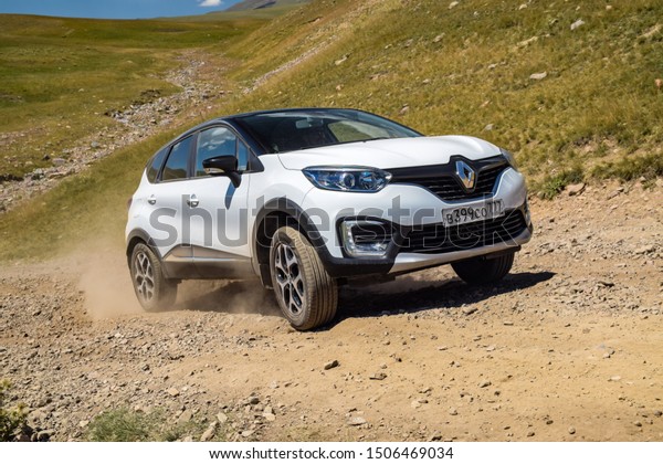 ALMATY, KAZAKHSTAN - JULY 20, 2019:\
Affordable Russian made SUV Renault Kaptur drives off road in\
Kazakstan. The SUV rides steep uphill on gravel and rocky path.\
Meadow landscape in the\
background.