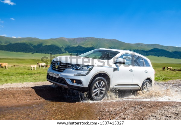 ALMATY, KAZAKHSTAN - JULY 20, 2019: Renault\
Koleos drives off road in Kazakstan. French SUV crosses a stream by\
wading. The front of the Koleos features large C-shaped LED daytime\
running lights.
