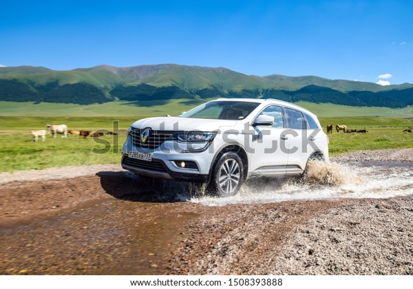 ALMATY, KAZAKHSTAN - JULY 20, 2019: Renault\
Koleos drives off road in Kazakstan. French SUV crosses a stream by\
wading. The front of the Koleos features large C-shaped LED daytime\
running lights.