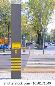 Almaty, Kazakhstan - Sep 22, 2017: Modern traffic light for controlled pedestrian crossing (Kazakh, Russian & English instructions) & striped 'zebra' against street with green trees. Selective focus