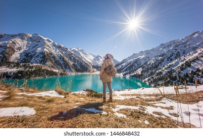 ALMATY, KAZAKHSTAN: A young lady standing in front of spectacular scenic Big Almaty Lake ,Tien Shan Mountains in Almaty, Kazakhstan during late autumn, winter.