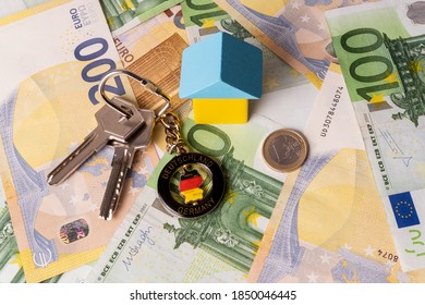 Almaty, Kazakhstan,11/07/2020. Keys with a keychain in the form of a circle with a map of Germany,  schematic house made of children's cubes, a one euro coin against the background of 200 and 100 euro