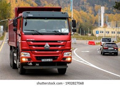 Almaty, Qazaqstan - Oktober, 02, 2020: Red Chinese dump truck CNHTC Howo Sinotruk driving down the Almaty street