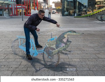 ALMERE, NETHERLANDS - 27 OCT. 2015: Unknown Man Shows The Power Of 3D Optical Illusion Of A Street Painting By An Unknown Artist. Once A Year The City Allows Artists To Make Paintings On The Streets