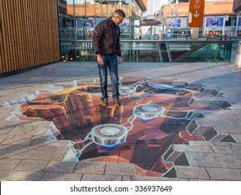 ALMERE, NETHERLANDS - 27 OCT. 2015: Unknown Man Shows The Power Of 3D Optical Illusion Of A Street Painting By An Unknown Artist. Once A Year The City Allows Artists To Make Paintings On The Streets