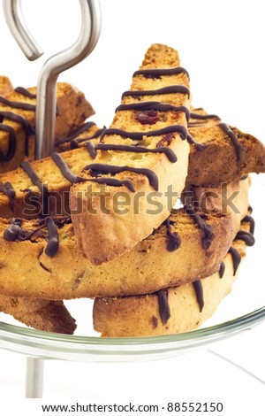 Almond Cranberry Biscotti with drizzled chocolate on cake stand with white background, in vertical format