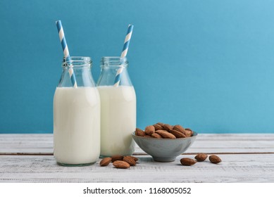 Almond milk in bottles with almonds and drinking straws on blue background - Powered by Shutterstock