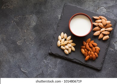 Almond Milk In A Clay Pot And Fresh Nuts Over Dark Slate Background, Selective Focus. Dairy-free, Vegan Healthy Food Concept Top View With Copy Space