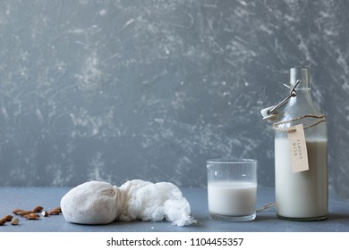 Almond Milk In Glass With Nut Milk Bag And Almonds On Wooden Background With Copy Space.