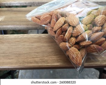 Almond Nuts In Plastic Bag On Wood Background