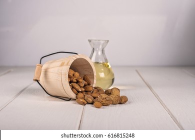 Almond oil and bowl of almonds on white wooden