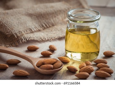 Almond oil in glass bottle and almonds on wooden table