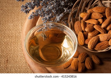 Almonds And Almond Oil On Wooden Background. Skin And Hair Care Concept. Lavender And Nuts.