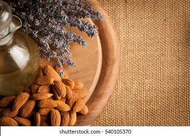 Almonds And Almond Oil On Wooden Background. Skin And Hair Care Concept. Lavender And Nuts.