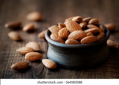 Almonds in a black bowl against dark rustic wooden background - Shutterstock ID 564583588