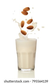 Almonds Falling Into Almond Milk. A Glass Of Almond Milk On A White Surface. 