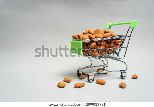 Almonds and nut kernels are in the basket and cart\
of the hypermarket.Isolate on a gray background.copy \
space