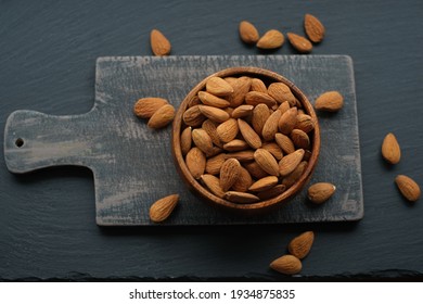 Almonds nuts  in a round wooden cup on a black shabby chic board on a black schiffer  background.Nuts and seeds. .Healthy fats.Heap Almonds shelled  nut closeup.Tasty organic snack 