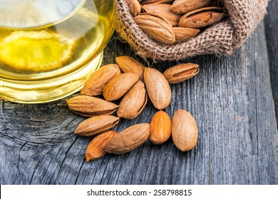 Almonds and oil on rustic wooden background.