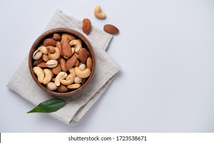 almonds, pistachios and cashews are placed in a wooden bowl on a linen napkin on a light grey background. Top view and copy space. Horizontal orientation - Shutterstock ID 1723538671