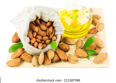 Almonds in the sack, almond oil and green leaves on mat isolated on white background