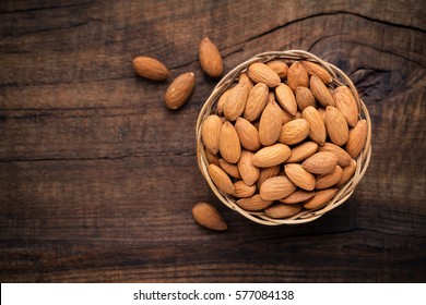 Almonds In Willow Bowl Against Dark Rustic Wooden Background. Overhead View